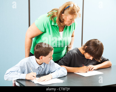 Enseignant observe deux garçons de l'école afin de s'assurer qu'ils ne sont pas tricher sur un test. Banque D'Images