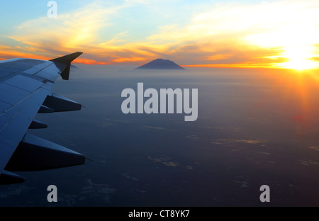 Le lever du soleil sur la côte Est de Bali vu de l'avion à réaction. Mont Agung en arrière-plan. Banque D'Images