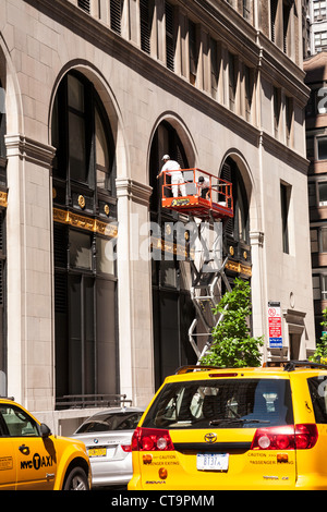 Les travailleurs remplissant la restauration des édifices sur plateforme élévatrice, NYC Banque D'Images