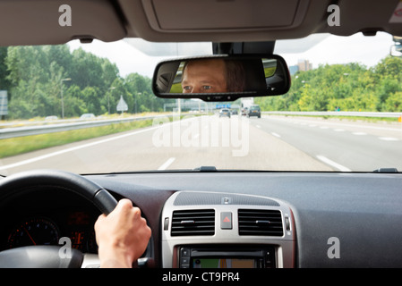 L'homme, conduire une voiture, avec ses yeux reflétaient dans le rétroviseur Banque D'Images