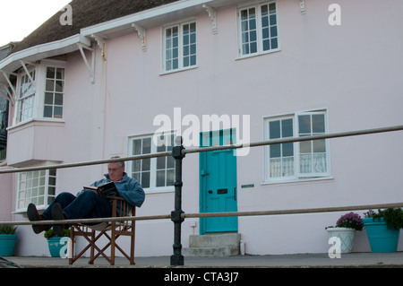 La lecture de l'homme à l'extérieur chambre sur la promenade à Lyme Regis Dorset UK Banque D'Images