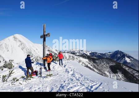 Trois personnes avec ski debout à croix sur sommet de Breitenstein, Geigelstein Kampenwand et en arrière-plan, Breitenstein, Chiem Banque D'Images