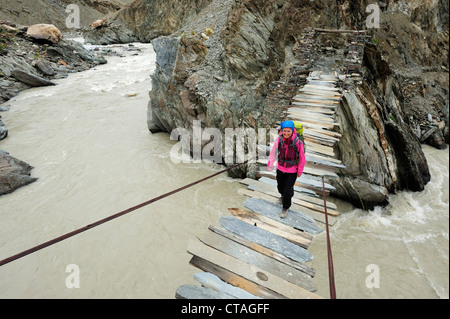 Woman crossing river sur le pont suspendu, entre Phuktal et Testa, plage du Zanskar, Traverse, Zanskar, Ladakh Zanskar, gamme, Ja Banque D'Images