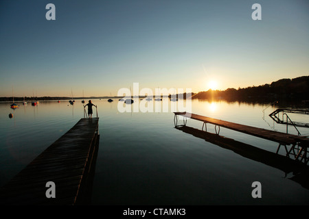 L'enfant sur une jetée en bois au coucher du soleil, le lac Woerthsee, Starnberg, Haute-Bavière, Bavière, Allemagne Banque D'Images