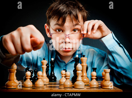 Nerd jouer aux échecs sur un fond noir Banque D'Images