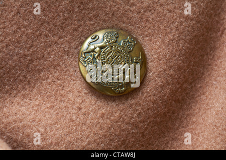 Bouton décoratif doré avec devise Dieu et mon droit Et bouclier des armoiries du Royaume-Uni Sur le manteau en laine brun Daniel Hechter Banque D'Images