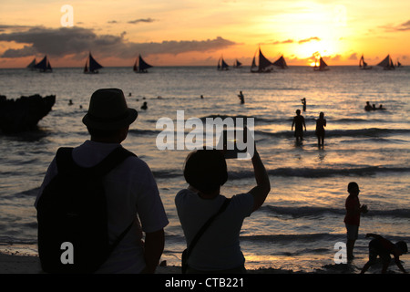 Deux touristes prendre des photos au coucher du soleil, Boracay, île de Panay, Visayas, Philippines Banque D'Images