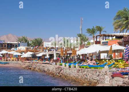 Vue du front de mer de la baie de Dahab avec les vacanciers de vous détendre sur des chaises longues , Dahab, Egypte Banque D'Images