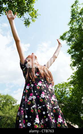 Fille de l'adolescence avec les mains posées contre blue cloudy sky Banque D'Images