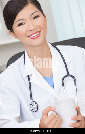 Une femme d'origine asiatique chinois médecin de boire du thé ou du café dans un bureau de l'hôpital Banque D'Images