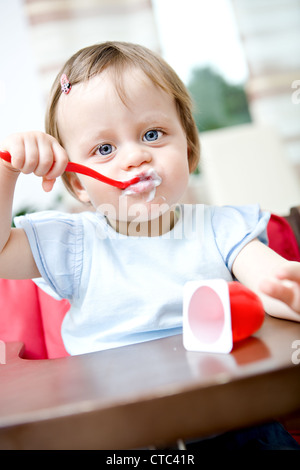 Little baby girl eating a yaourts Banque D'Images