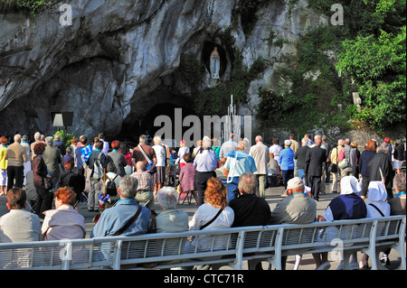 Pèlerins priant devant la grotte au Sanctuaire de Notre-Dame de Lourdes, Pyrénées, France Banque D'Images