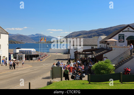 Bar et restaurant avec des gens assis à l'extérieur de la ville sur la côte west highlands Loch Broom en été. Ullapool Ecosse UK. Banque D'Images