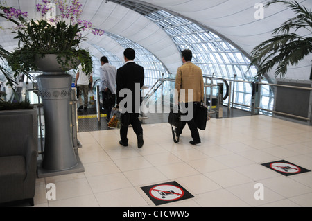 Les hommes d'Asie à pied de l'escalator, l'aéroport de Suvarnabhumi, à Bangkok, Thaïlande. Banque D'Images