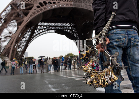 Un homme de vendre illégalement Tour Eiffel souvenirs devant la tour (venant de Trocadéro) près de la Tour Eiffel à Paris, France. Banque D'Images