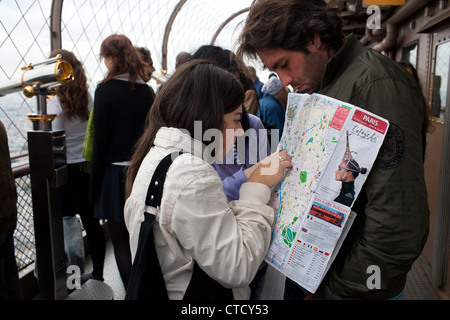 Les touristes avec un plan de Paris au deuxième étage de la Tour Eiffel à Paris, France. Banque D'Images