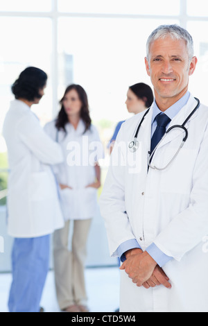 Mature doctor croisant ses mains devant son équipe Banque D'Images