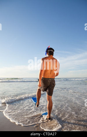 Jeune homme portant un équipement de plongée libre en marchant dans l'eau Banque D'Images