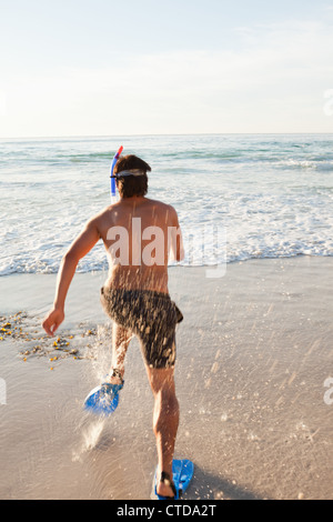 Jeune homme en marche dans l'eau avec palmes Banque D'Images
