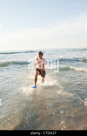 Jeune homme heureux tournant dans l'eau avec palmes Banque D'Images
