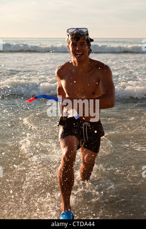 Jeune homme heureux de porter un équipement de plongée libre lors de l'exécution dans l'eau Banque D'Images