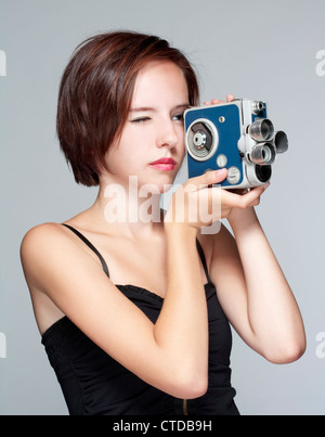 Adolescente avec un vieil appareil photo 35 - isolé sur gris Banque D'Images