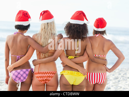 Quatre amis avec leurs bras autour de l'autre lors du port de Santa hats Banque D'Images