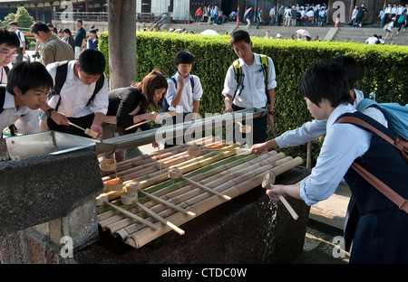 Des écoliers japonais exécutant le rituel de temizu (purification) avant d'entrer dans le temple bouddhiste de Todai-ji, à Nara, Japon. Banque D'Images