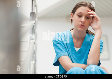Les infirmières s'appuyant sa tête sur ses mains dans une cage d'escalier Banque D'Images
