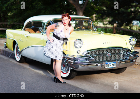 Un modèle pin up pose à côté d'un véhicule classique Banque D'Images