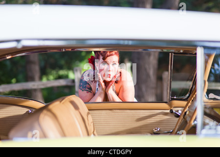 Cute pinup model looking en voiture classique Banque D'Images