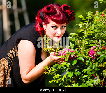 Style des années 1950 pinup model posing comme une épouse smelling flowers Banque D'Images