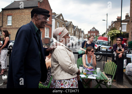 Une vieille black couple font leur chemin à travers le marché avec les buveurs de café à l'arrière du terrain. Banque D'Images