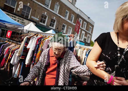 Une vieille femme a aidé à travers le marché. Marché de Broadway à Hackney, East London est devenu très un populaire de la rue du marché. Banque D'Images