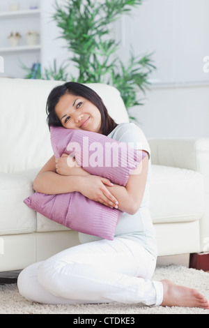 Femme tenant un oreiller tout en restant assis sur le sol Banque D'Images