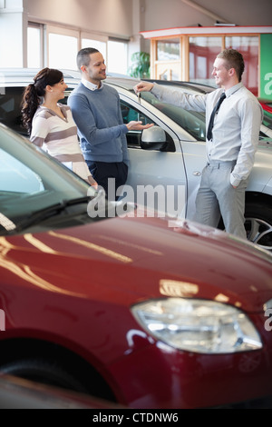 Smiling salesman touches donnant à un couple heureux Banque D'Images