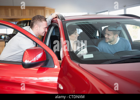 Couple à un vendeur, assis sur une voiture Banque D'Images