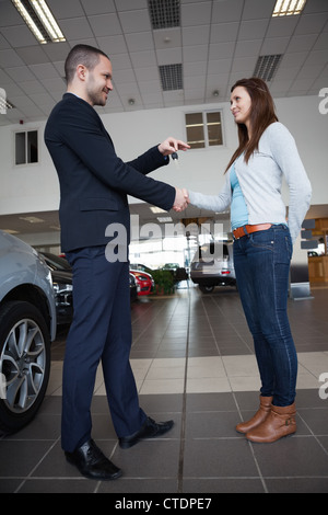 Vendeur en donnant des clés de voiture et en agitant la main d'un client Banque D'Images