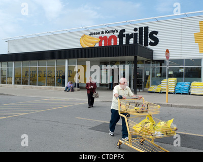 Un homme âgé en poussant un chariot à l'extérieur de Jesse & Kelly's No Frills magasin supermarché de l'Ontario, Canada, Amérique du Nord Banque D'Images