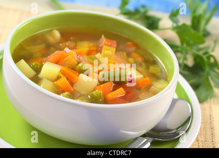 Soupe de légumes frais du haricot vert, pois, carotte, pomme de terre, poivron rouge, tomate et poireau dans un bol avec le persil dans l'arrière Banque D'Images