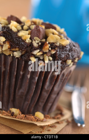 Muffin chocolat-noyer avec une tasse à café à l'arrière (Selective Focus, Focus sur le bord avant de la muffin) Banque D'Images