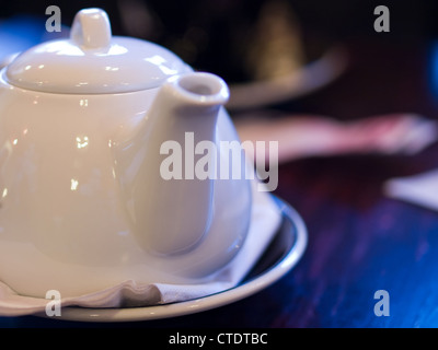 Théière en porcelaine blanche de la vie encore avec une tasse en arrière-plan. Banque D'Images