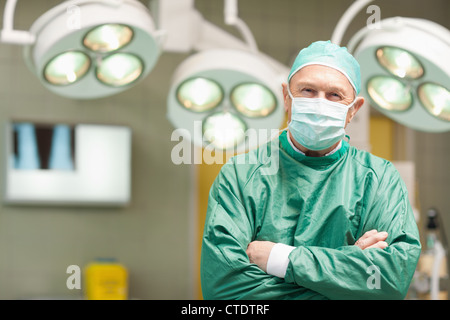 Smiling surgeon croisant les bras en position debout Banque D'Images