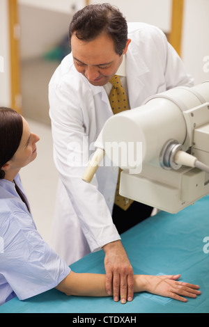 Smiling doctor plaçant le bras d'un patient sur une table Banque D'Images