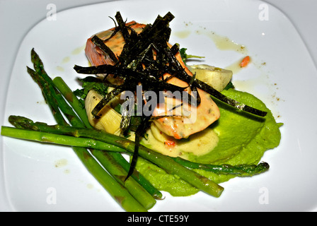 Le saumon quinnat cuit asperges artichauts algues frits au citron purée de greenpea sauce à l'aneth plat principal fruits de mer Banque D'Images