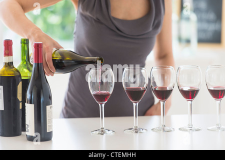 USA, New Jersey, Jersey City, femme le ronronnement du vin rouge dans des verres à vin Banque D'Images