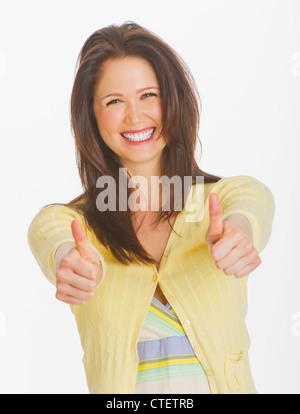 Portrait of smiling young woman showing Thumbs up, studio shot Banque D'Images
