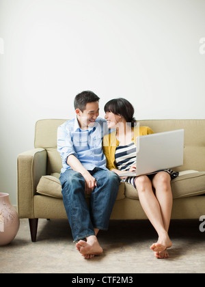 USA, Utah, Salt Lake City, Young happy couple sitting on sofa Banque D'Images