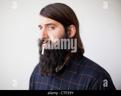 Jeune homme barbu avec broken cigarette dans sa bouche Banque D'Images