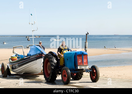 Tirez sur leur bateau de pêche pêcheur le halage sur la plage de Redcar, UK Banque D'Images